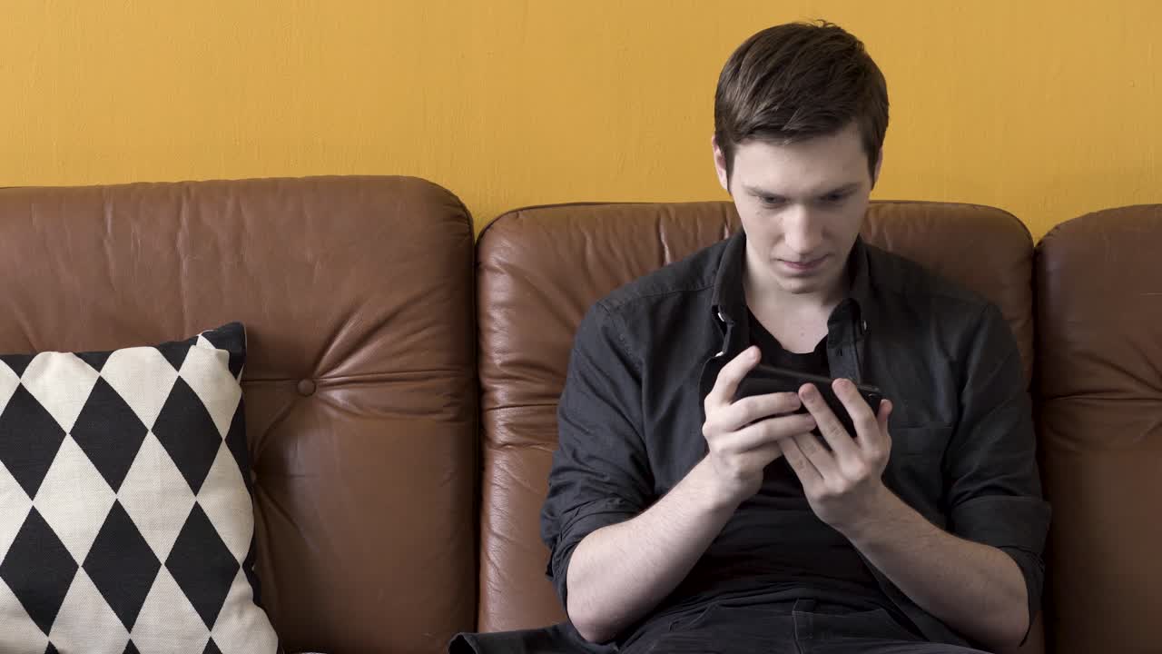 소파에서 스마트폰을 사용하는 젊은 남자
