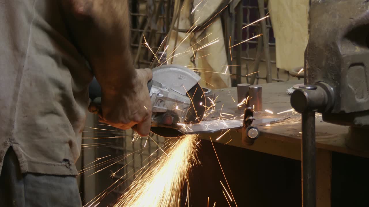 원형 도자기를 만드는 사람: 뜨거운 금속에서 불꽃이 날아오는 사람: 사람의 열심히 일하는 사람: 작업장에서 강철을 작업하는 사람: 손과 전기 도자기의 클로즈업 - 금속, 손 도구의 클로스업