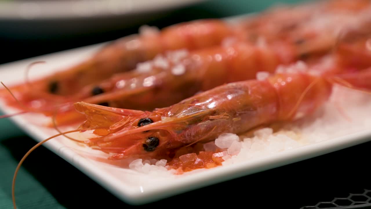 바다 소금으로 뿌려진 맛있는 가정용 오븐에서 요리 된 은 새우의 클로즈업 뷰가 미니멀한 색 접시에서 중심을 차지합니다.