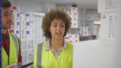 trabajadora en un almacén de distribución logística que toma una caja de la estantería