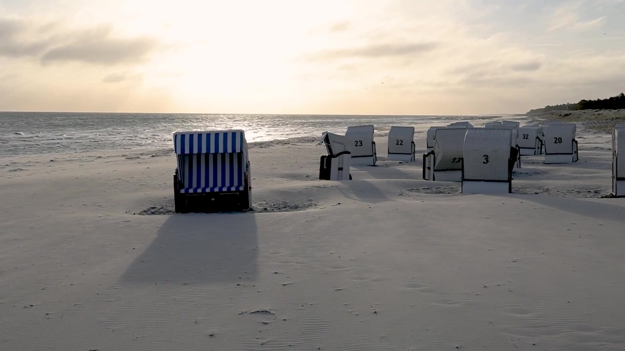 Tomme strandstole bades i den opgående sols lys på stranden ved Østersø-feriebyen Prerow på Darss (Nationalpark Vorpommersche Boddenlandschaft).