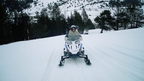 snowmobiles on snowy road in the forest. group of friends doing perfect leisure mountain activity, with a woman driving a snowmobile 4k