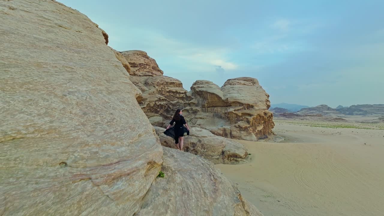 rocas antiguas con una mujer de pie en el área protegida de wadi rum en el sur de jordania, oriente medio