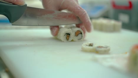 cook cuts a japanese roll with salmon