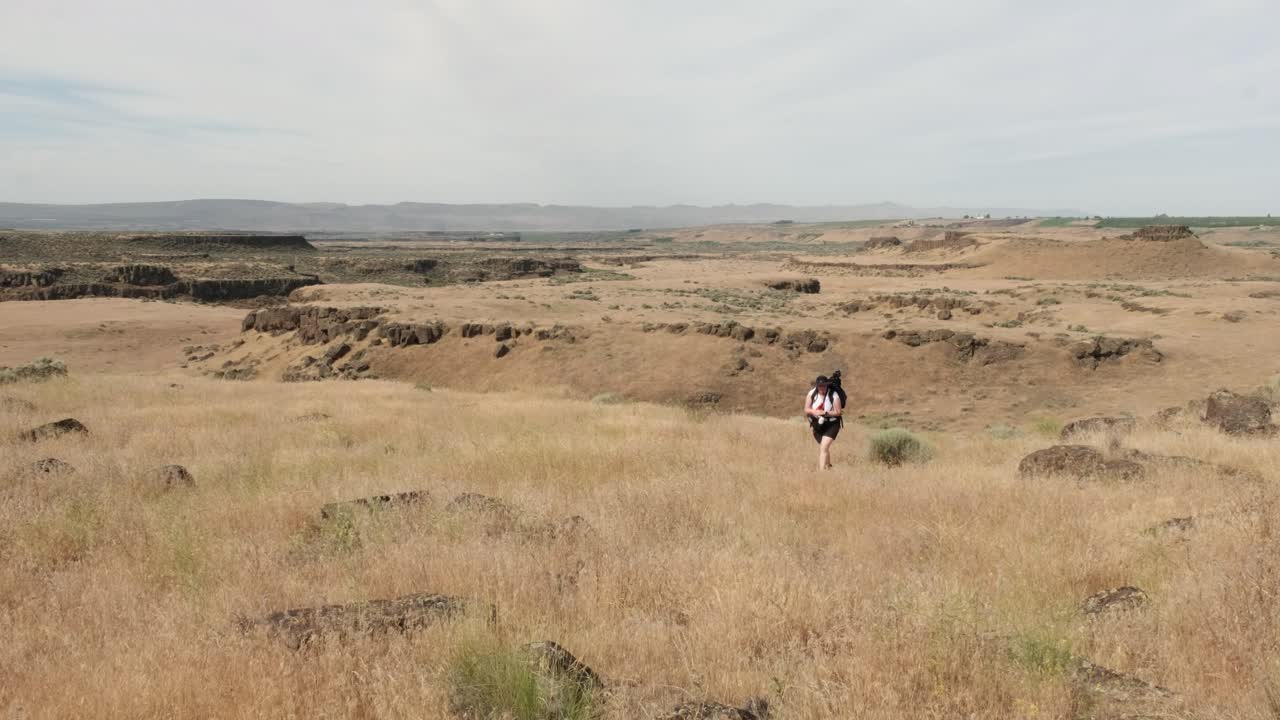mujer con trípode en mochila caminatas praderas áridas de wa scablands