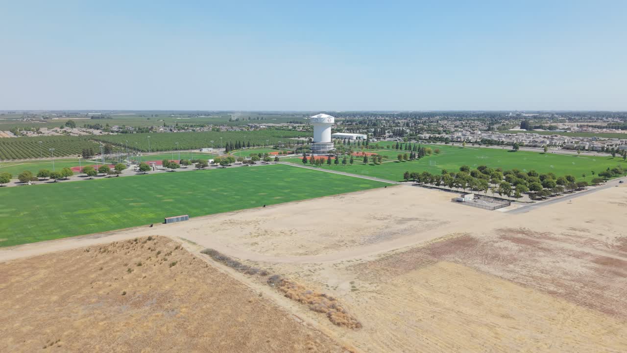 Aerial tracking shot moving over farmland toward water tower and city in Ripon California