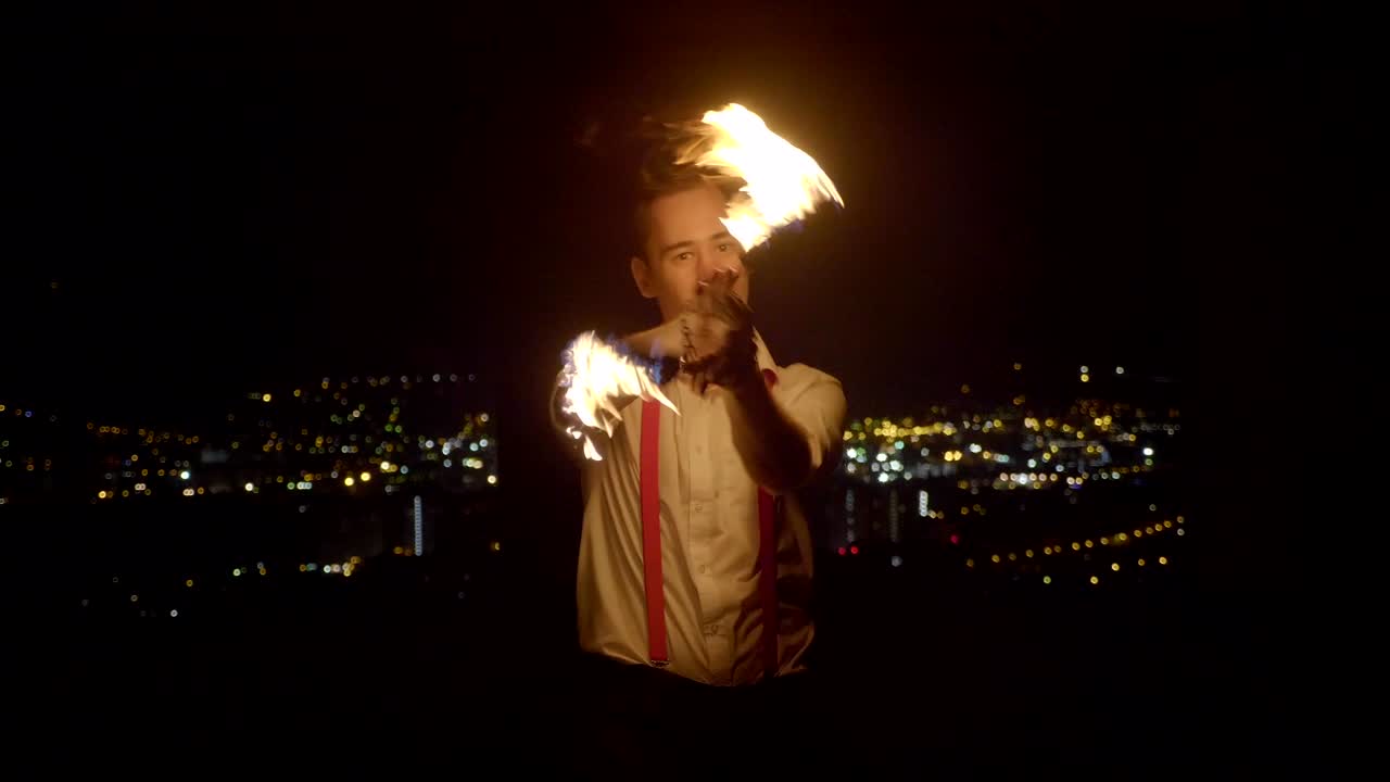 artista masculino realizando un espectáculo de fuego en la oscuridad en cámara lenta