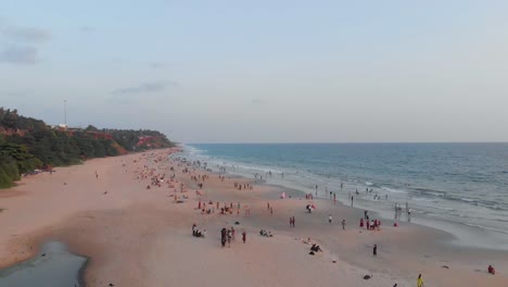 rotating aerial view showing large number of tourists enjoying their holiday on varkala beach during day