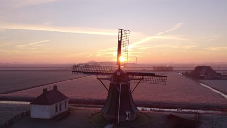 amazing shot of iconic windmill with sun shining through blades, aerial