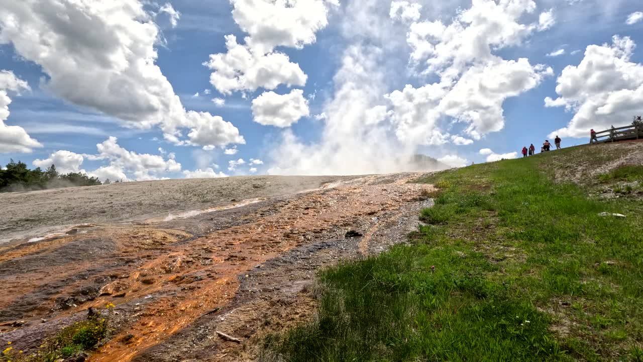 Tourists Visiting The Upper Geyser Basin Trail In Yellowstone National Park, Wyoming, USA. Liquid Run Off Streaming Down The Hillside.