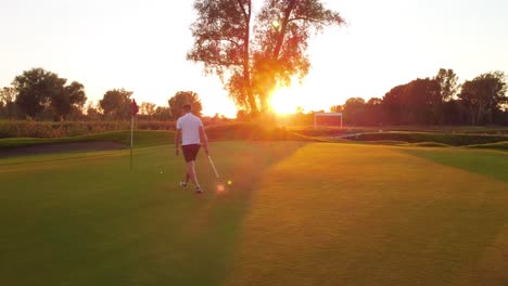 Das-Letzte-Putten-Auf-Dem-Grün-Eines-Golfspielers-Auf-Dem-Golfplatz-Während-Eines-Sonnigen-Sonnenuntergangs