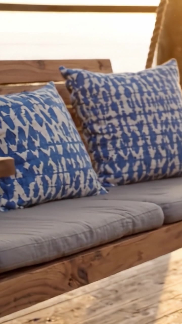 Un'altalena da esterno accogliente e invitante con eleganti cuscini a fantasia blu, perfetta per il relax e per godersi panorami mozzafiato in un ambiente sereno.