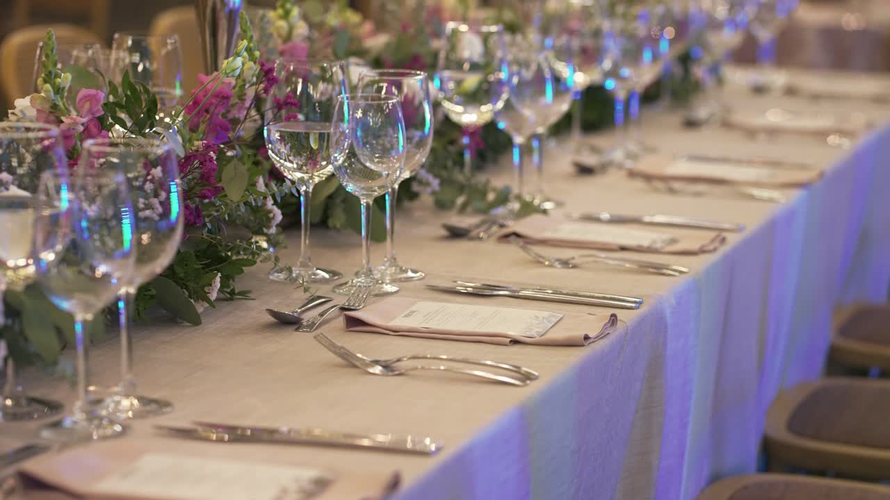 Long wedding reception table elegantly set with floral centerpiece, glassware, and cutlery