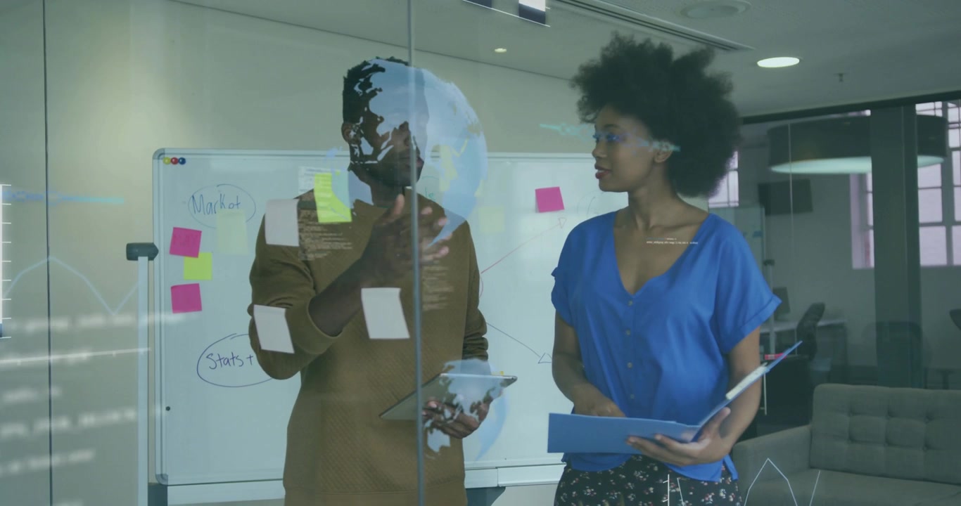 Woman placing note and sharing market plan on glass, man tapping tablet animating data overlays