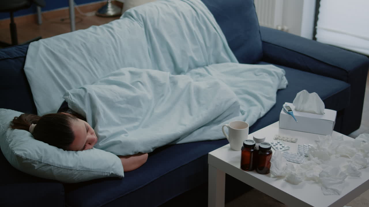 Person with disease sleeping wrapped in blanket on sofa