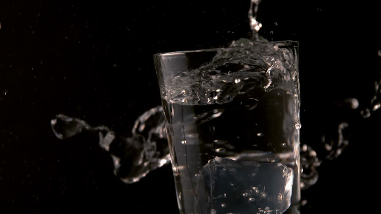 Cubetti di ghiaccio che cadono in un bicchiere d'acqua
