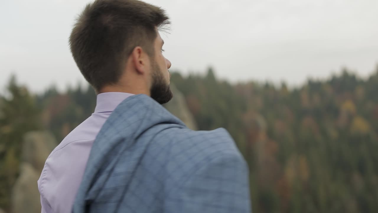 산의 언덕에 있는 재을 입은 젊은 남자. 사업가. 신부. 신부