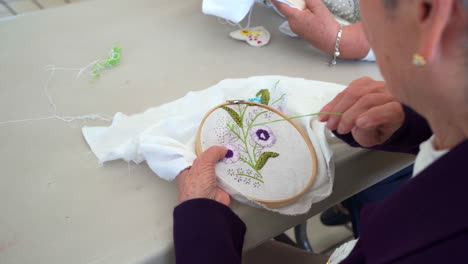 elder embroidering flowers in art class