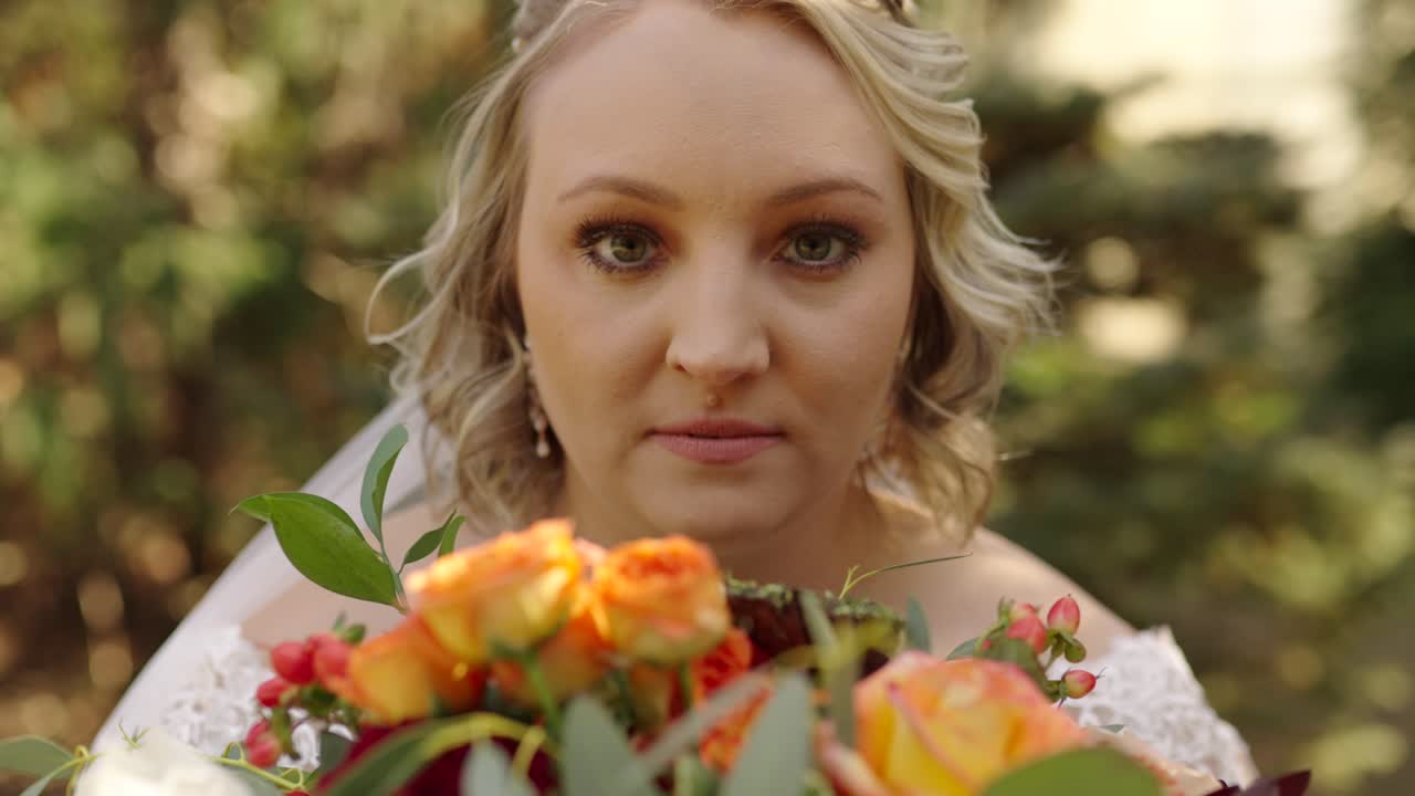 la sposa alza lo sguardo dal bouquet di fiori e rivela il suo viso