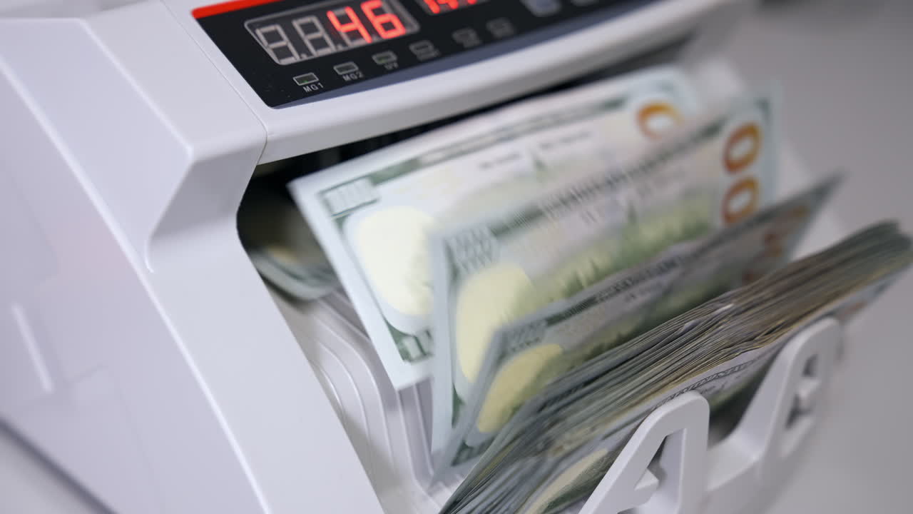 Electronic money counter machine is counting is counting the American hundred-dollar banknotes. The world currency is the US dollar.