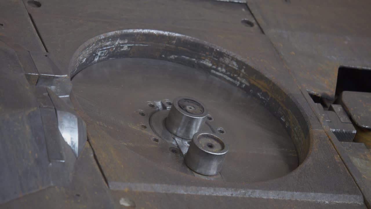 Steel bar being shaped and cut on a heavy metal machine at an industrial workshop.