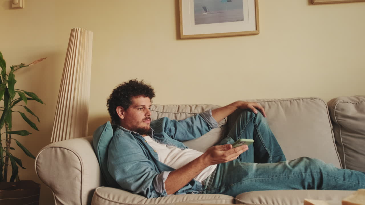 Uomo che si rilassa sul divano usando lo smartphone