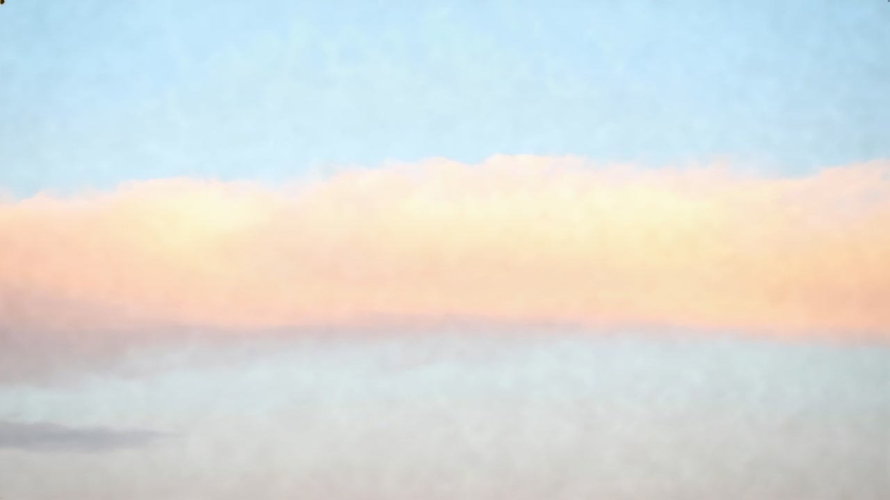 Glowing cloud band reacting to low sun, shifting pink-orange and gray tones at horizon