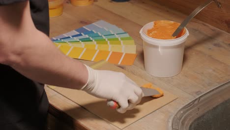 a worker applies a paint sample to a palette for color verification