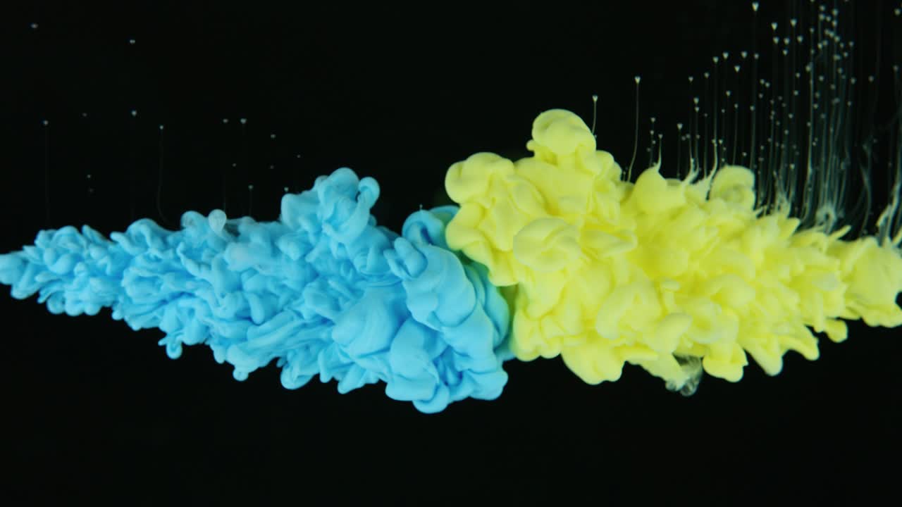 노란색과 파란색 잉크 구름이 검은색 바탕에 물 에서 충돌합니다.