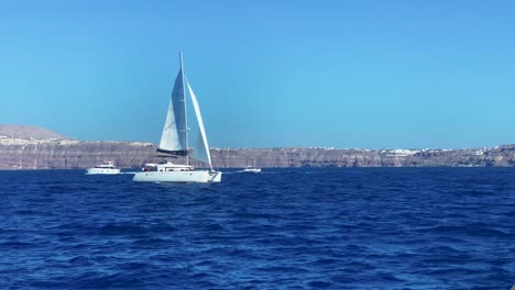 Yate-Catamarán-De-Lujo-Y-Barcos-Navegando-En-El-Paisaje-Marino-De-La-Isla-De-Santorini,-Grecia