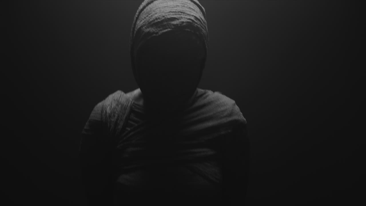 A mummy of a woman on a dark backdrop rises her head