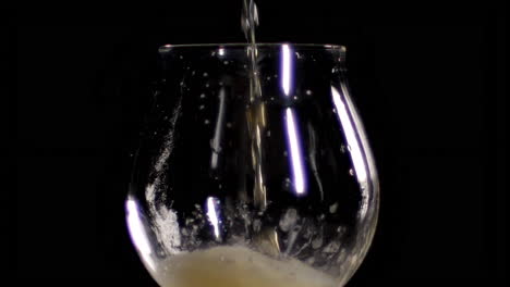 Slow-Motion-Close-up-of-craft-Beer-being-poured-in-to-an-empty-tulip-glass,-black-background