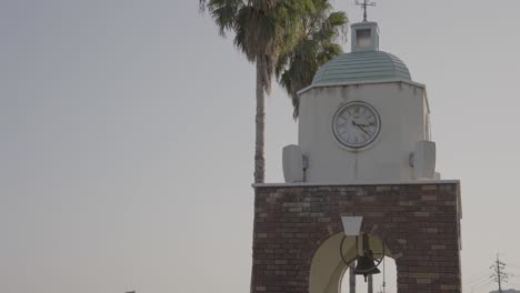 Campana-Y-Torre-Del-Reloj-Sonando-En-Cámara-Lenta,-Escena-Cálida-Al-Aire-Libre