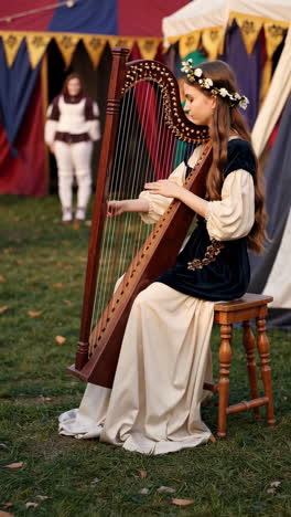 a young woman in historical costume playing a harp at an outdoor event