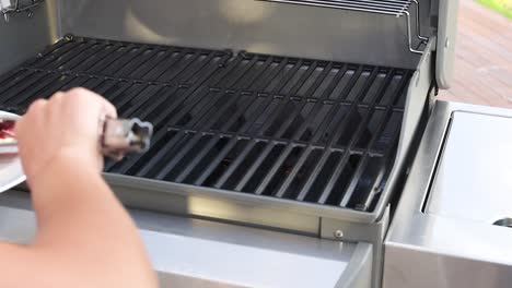 a person places raw beef steak on a grill, preparing for outdoor cooking under natural light
