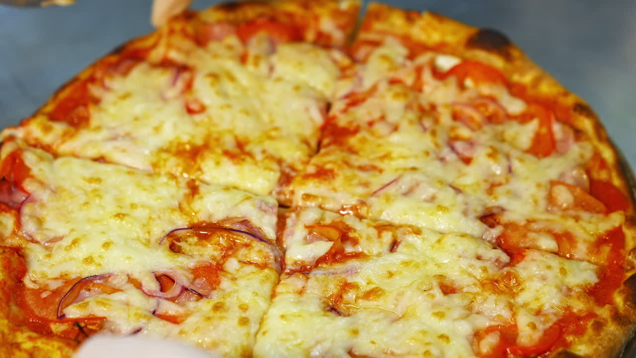 Tagliare la pizza prima di servire. Preparare cibo italiano nella cucina del ristorante.