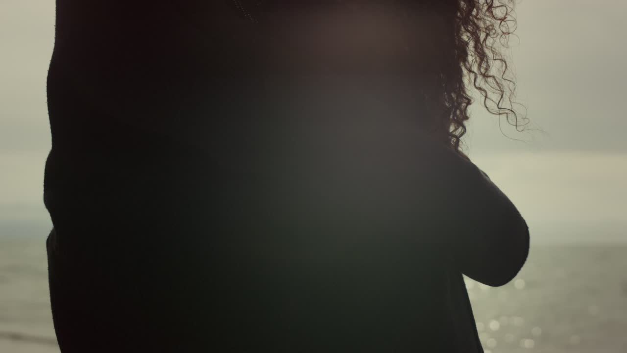 해변에서 서로 포옹하는 두 사람. 커플의 손이 민족의 곱슬 머리카락을 만 ⁇ 니다.