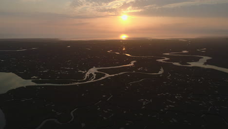 Erstellen-Einer-Filmischen-Drohnenaufnahme-Von-Natürlichen-Salzwiesen-Und-Bächen-Bei-Flut-Mit-Gewundenen-Wasserstraßen-Bei-Atemberaubendem-Orangefarbenem-Sonnenaufgang-An-Der-Ostküste-Von-North-Norfolk,-Großbritannien