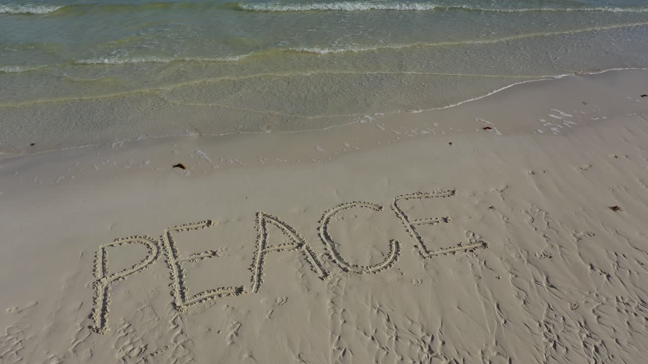 모래에 새겨진 평화를 보여주는 항공 카메라가 작아지면서 멀어집니다.