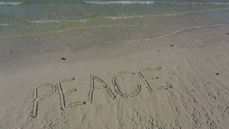 aerial camera showing peace inscribed in the sand and then pulls away as it gets smaller