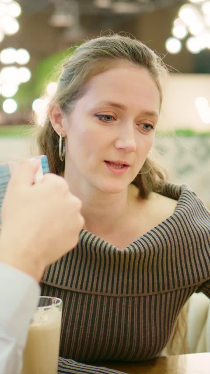 Un momento di riflessione: una donna si dedica alla contemplazione mentre conversa bevendo qualcosa, mettendo in risalto l'introspezione e la connessione sociale in un ambiente accogliente
