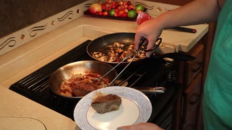 mujer sirviendo bistec, cebollas asadas y champiñones miatake salteados en una pequeña cocina casera