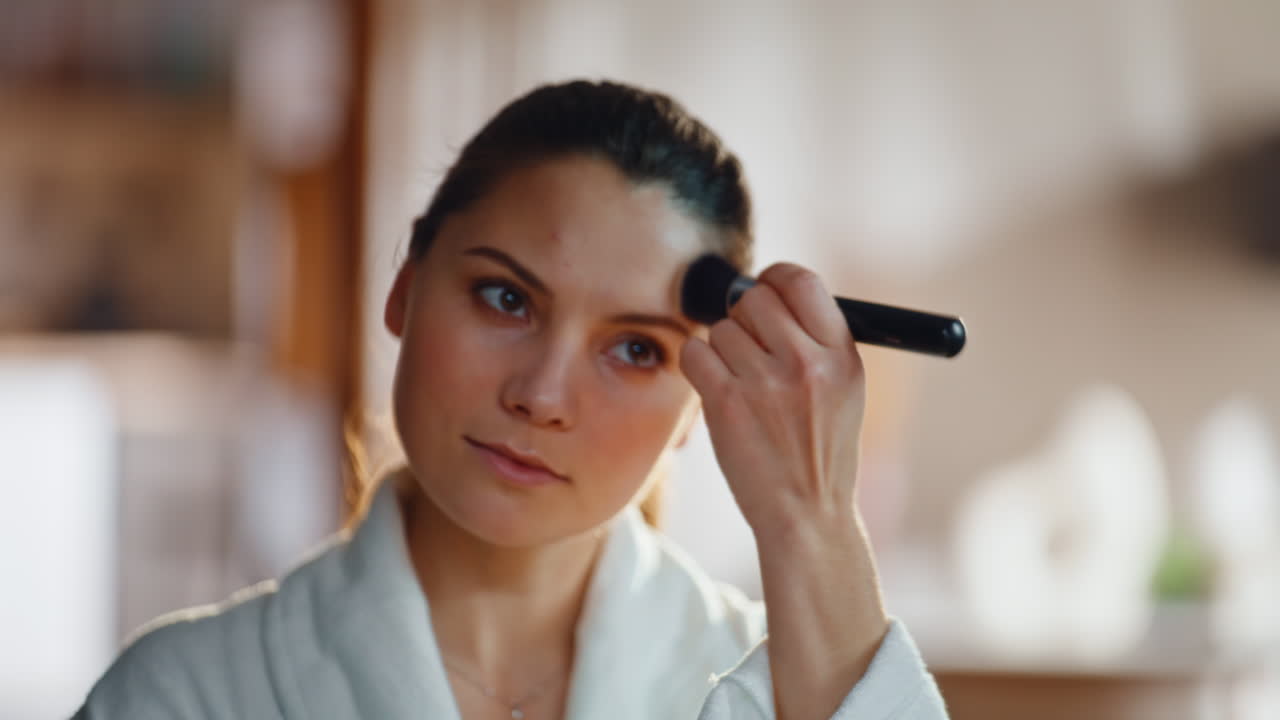 Woman powdering face looking in bathroom mirror closeup. Relaxed lady