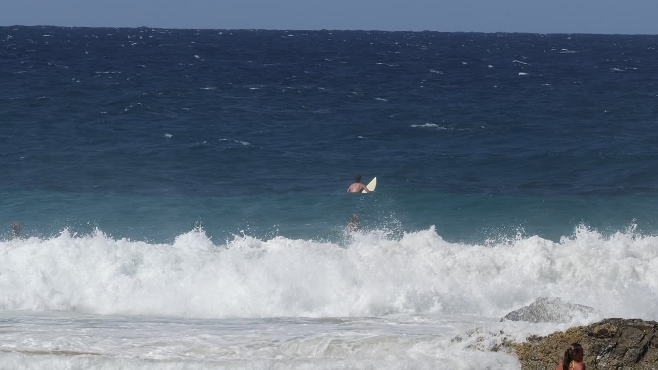 서퍼들은 바위 근처에 있는 큰 파도와 상호 작용합니다.