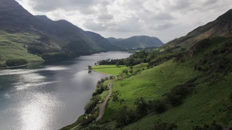 Disparo-De-Un-Dron-Volando-Hacia-Atrás-A-Lo-Largo-De-Las-Colinas-Junto-Al-Agua-De-Crummock-En-Un-Día-Soleado,-Distrito-De-Los-Lagos,-Cumbria,-Reino-Unido