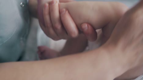 un pediatra experto realiza un masaje de las piernas del bebé en la mesa