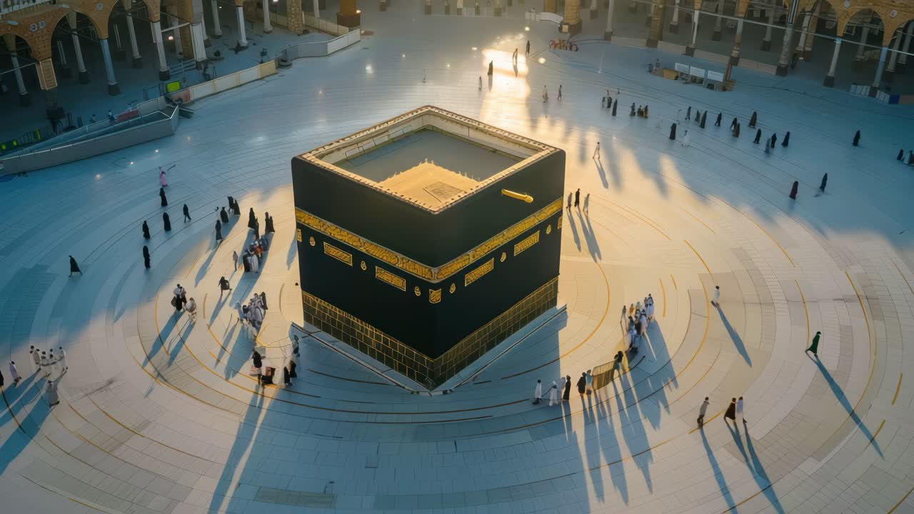 Aerial view of the Kaaba surrounded by people casting long shadows