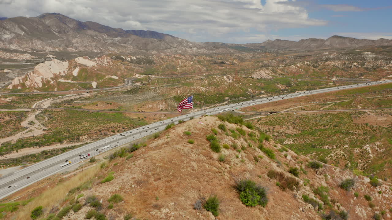 bandera estadounidense en la cima de una colina cerca de la autopista 15 cerca de phelan, california