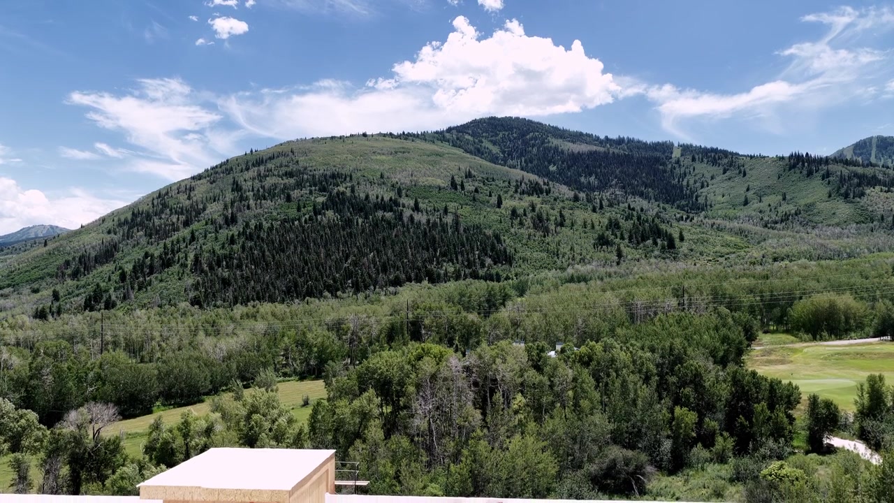 Rivelazione aerea con drone in discesa di un nuovo complesso residenziale in costruzione a Park City, Utah, sullo sfondo delle lussureggianti e verdi montagne Wasatch.