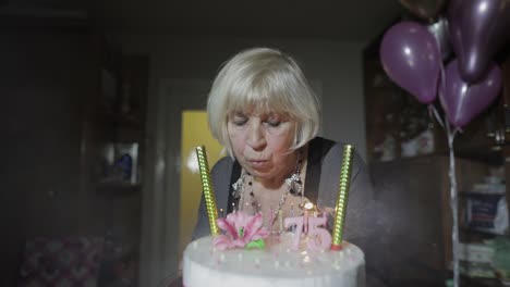 happy senior woman holding cake. celebrating. blowing birthday candles